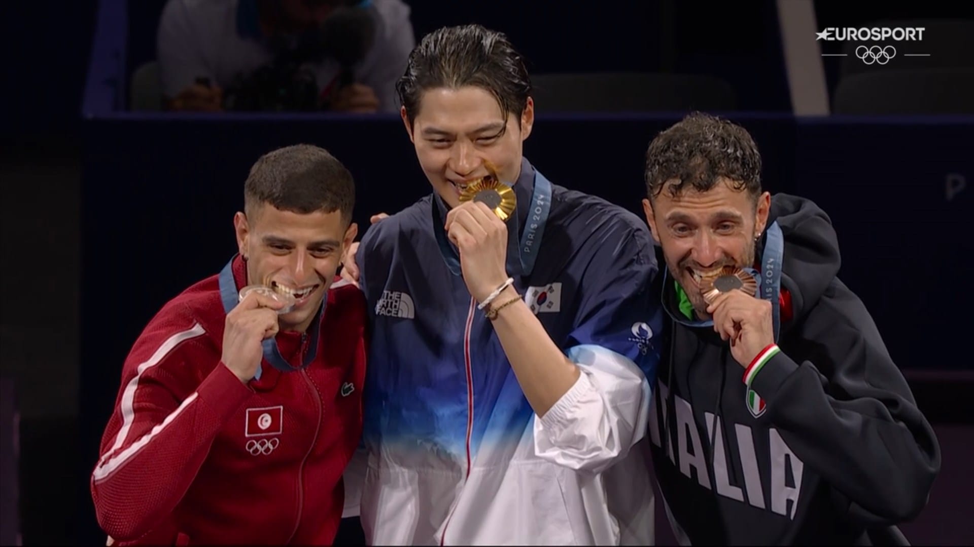 Fares Ferjani (g), S. Oh (c) et L. Samele (d) mordent leur médaille sur le podium du Sabre